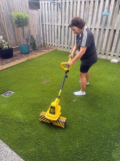 Garland 141-W cordless artificial lawn sweeper in use on small backyard synthetic grass